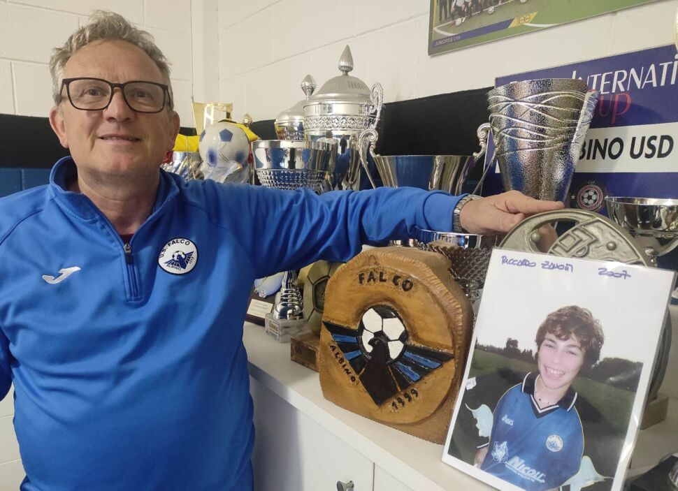 Mister Arizzi guardando la foto di Richi dei Pinguini Tattici Nucleari, centravanti dei suoi esordienti